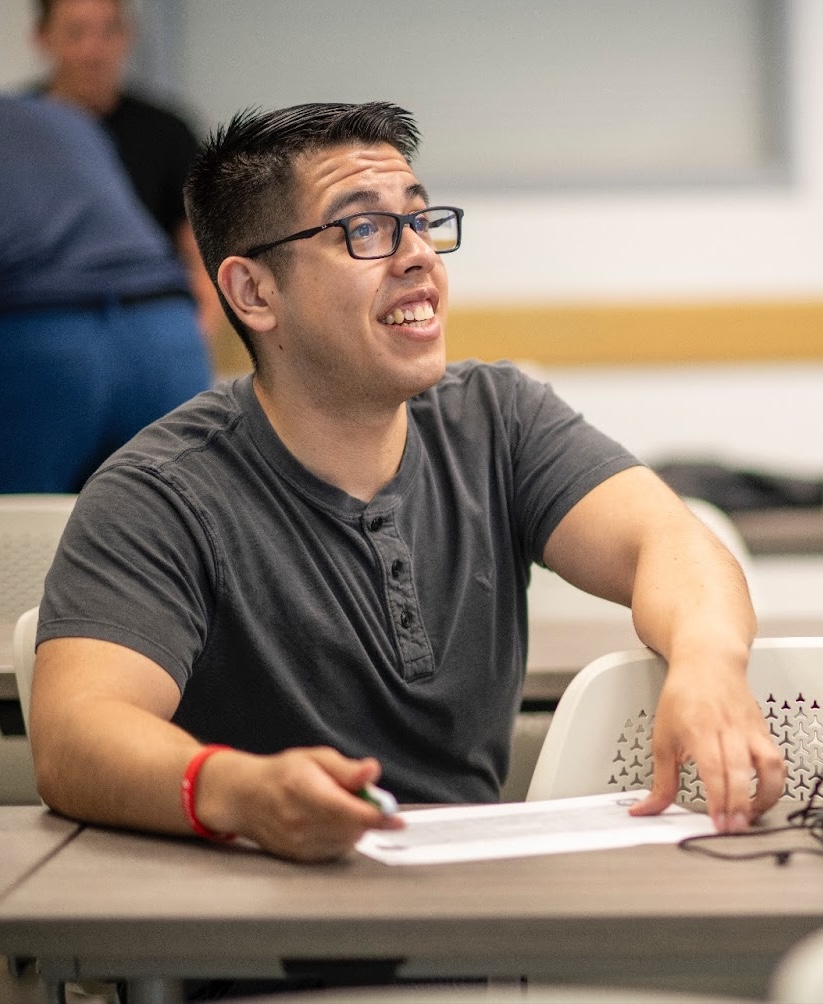 Our Purpose is help students like this one from UNT. Student is sitting in class, smiling.