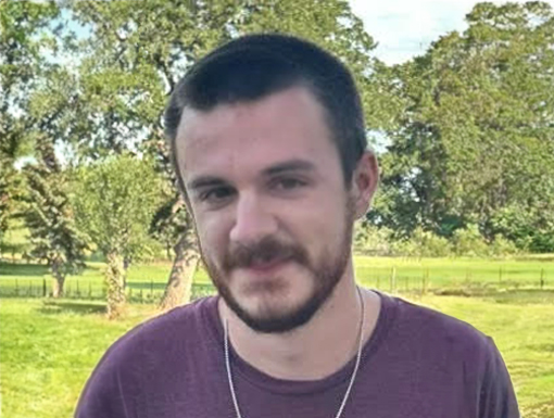 Christian Turner smiling at camera while standing in a grassy field.